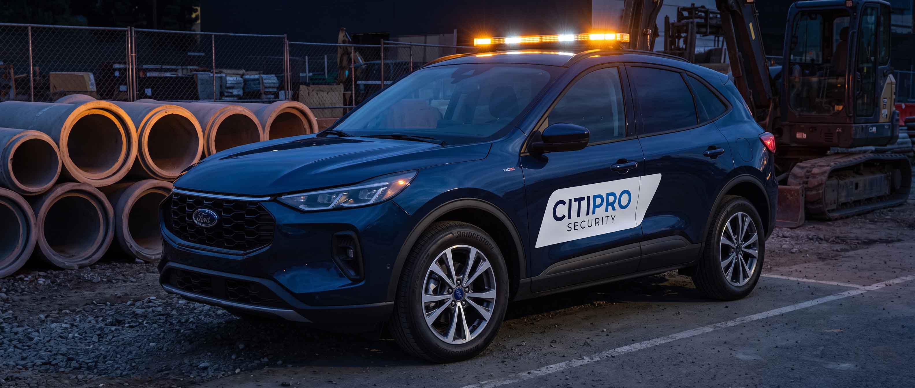 CITIPRO mobile patrol vehicle with roof light bar active, parked at a construction site in the evening